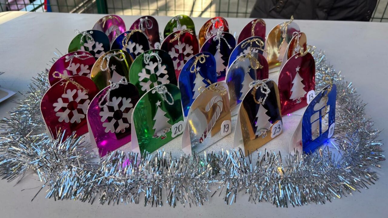 Les calendriers de l'Avent en papier métallisé présentés sur la table de vente, avec leurs rubans dorés et argentés.